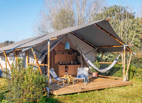 Luxus-Zelt mit Holzterrasse, Hängematte und Gartenstühlen im Wecamp Santa Cristina in Katalonien, Spanien.