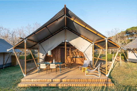 Tente glamping à Wecamp Santa Cristina, Catalogne, Espagne, avec terrasse en bois et espace détente.