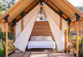Glamping tent met houten bed bij Wecamp Santa Cristina, een vakantiepark in Catalonië, Spanje.