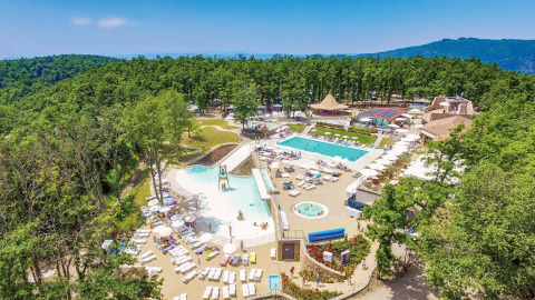 Vue aérienne du Chianti Glamping Resort en Toscane, Italie, avec piscines et transats entourés de forêt.