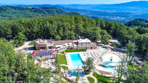Vista aerea di Chianti Glamping Resort in Toscana con piscine, natura rigogliosa e paesaggio collinare panoramico.