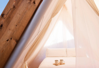 Vista interna di una tenda glamping con letto matrimoniale e tazze al Wecamp Santa Cristina, Catalogna.