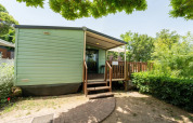 Vue extérieure du Cottage Classic au Weekend Glamping Resort en Italie avec terrasse en bois arborée.