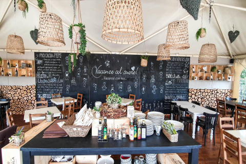Restaurant chaleureux avec menus sur ardoise et déco rustique au Chianti Glamping Resort en Toscane, Italie.