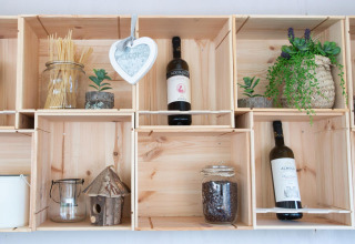 Houten planken met wijnflessen, planten en decoratie bij Chianti Glamping Resort in Toscane, Italië.