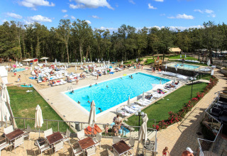 Außenpool und Liegestühle im Chianti Glamping Resort in der Toskana, Italien, mit vielen Gästen und Bäumen.