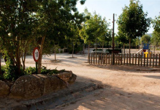 Playground area at Wecamp Santa Cristina Holiday Park in Catalonia, Spain, with trees, a fence and speed sign.
