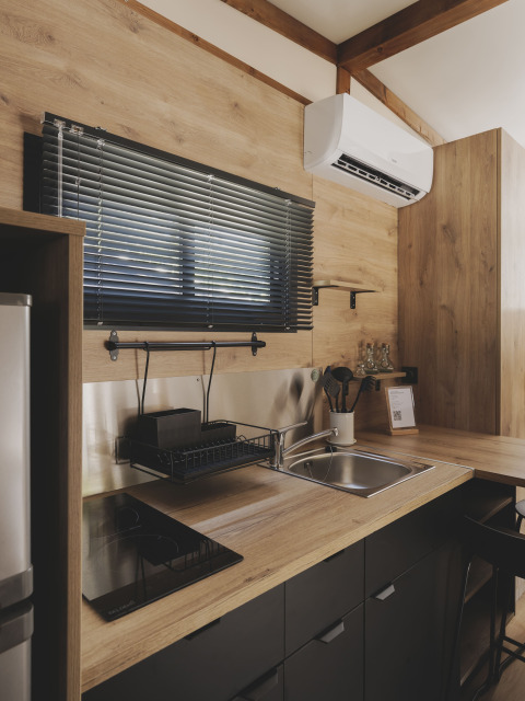 Moderne kitchenette in TINY HOME FAMILY bij Wecamp Jávea, Spanje, met hout en zwarte accenten.