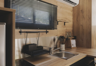 Moderne kitchenette in TINY HOME FAMILY bij Wecamp Jávea, Spanje, met hout en zwarte accenten.
