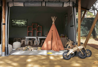Kinderbereich mit Tipi-Zelt, Holzbikes und Spielzeug im Wecamp Santa Cristina in Katalonien, Spanien.