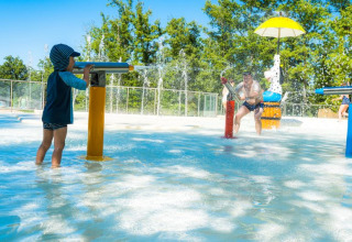 Kinder und Erwachsene spielen mit Wasserspielen im Chianti Glamping Resort in der Toskana, Italien.