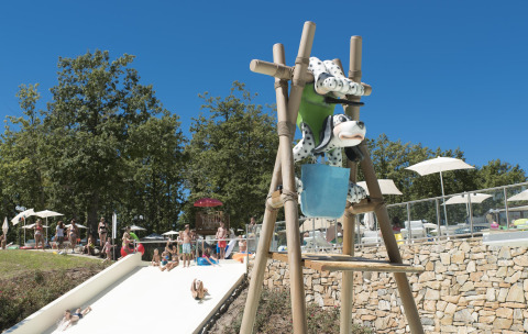 Enfants et adultes profitant des toboggans et du soleil au Chianti Glamping Resort en Toscane, Italie.