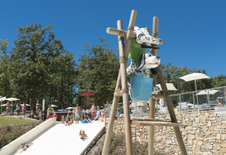 Familien entspannen im sonnigen Freibad mit Wasserrutsche im Chianti Glamping Resort in der Toskana.