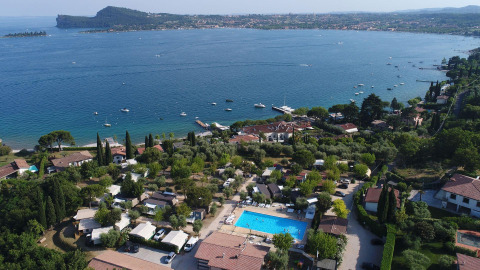 Aerial view of Vacanze Glamping Boutique holiday park in Lombardy, Italy, featuring a pool and lakefront scenery.