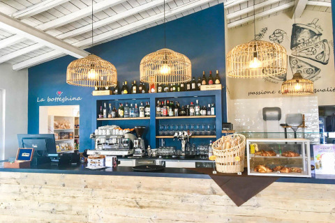 Inviting Italian café bar at Vacanze Glamping Boutique in Lombardy, Italy, with wicker lights and fresh pastries.