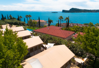 View of Vacanze Glamping Boutique in Lombardy, Italy, with tents, trees, and a stunning lake background.