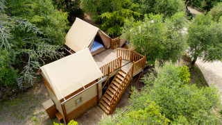 Vue aérienne d'une tente safari nommée Air Dreamer 3, entourée d'arbres avec une terrasse en bois.
