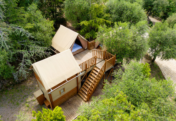 Vue aérienne d'une tente safari nommée Air Dreamer 3, entourée d'arbres avec une terrasse en bois.