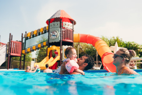 Family enjoying a pool with waterslide at Vacanze Glamping Boutique holiday park in Lombardy, Italy.