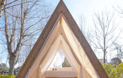 Triangular cabin tent at Wecamp Santa Cristina, Spain, with a cozy bed and daylight entering the tent.