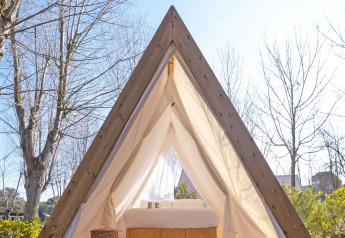 Triangular cabin tent at Wecamp Santa Cristina, Spain, with a cozy bed and daylight entering the tent.