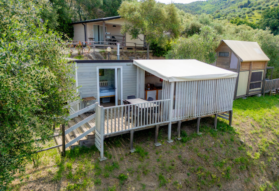 Cottage Clever Lodge med træterrasse i naturskønne omgivelser på en grøn bakke tæt på træer.