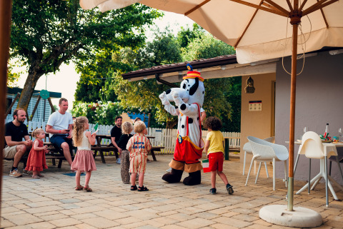 Children play with a costumed character outdoors as adults watch at Vacanze Glamping Boutique holiday park.