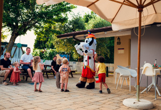 Children play with a costumed character outdoors as adults watch at Vacanze Glamping Boutique holiday park.