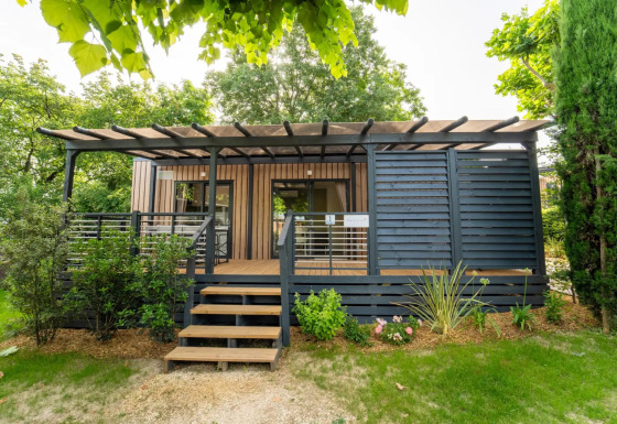 Vista exterior del Cottage Next XL Superior Dog, cabaña moderna de madera con terraza y jardines verdes.