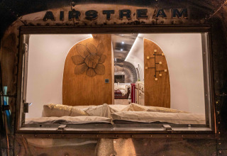 Uitzicht door het raam op het gezellige interieur van de Airstream tiny house bij Chianti Glamping Resort, Italië.