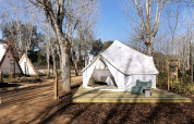 A Bell Tent safari tent at Wecamp Santa Cristina in Spain, surrounded by trees and outdoor seating area.
