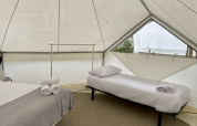 Innenaufnahme eines Bell Tent Plus Safari-Zeltes mit zwei Betten, Kissen und gerollten Handtüchern.