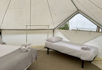 Innenaufnahme eines Bell Tent Plus Safari-Zeltes mit zwei Betten, Kissen und gerollten Handtüchern.