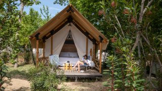 En person slapper af foran et safari telt i skoven ved Glamping Couple med moderne bekvemmeligheder.