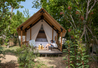 Una persona si rilassa davanti a una tenda safari presso Glamping Couple, immersa nella natura.