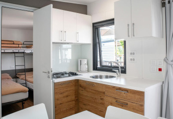 Alojamiento glamping moderno con cocina, comedor y dormitorio equipado con litera y cama doble.