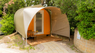 Tente safari Coco Couple avec terrasse extérieure, table et chaises, entourée de verdure.