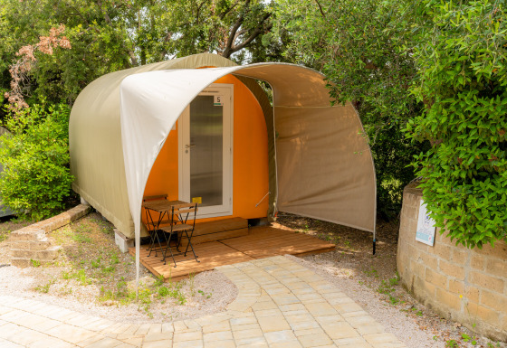 Safari-Zelt Coco Couple mit kleiner Terrasse, Tisch und Stühlen, umgeben von Bäumen und Natur.