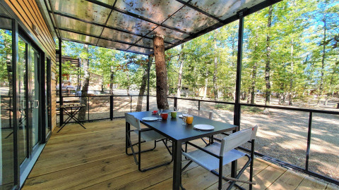 Terrasse extérieure du Next XL Panorama au Chianti Glamping Resort en Italie, avec table et vue sur la forêt.