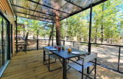 Terrasse des Next XL Panorama im Chianti Glamping Resort, Italien, mit Tisch, Stühlen und Waldblick.