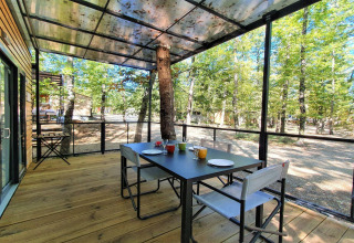 Terrasse extérieure du Next XL Panorama au Chianti Glamping Resort en Italie, avec table et vue sur la forêt.
