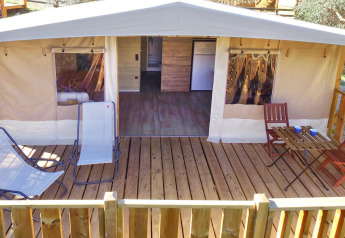Tenda Safari Lodge Deluxe con veranda in legno, sdraio e tavolo per un confortevole soggiorno glamping.