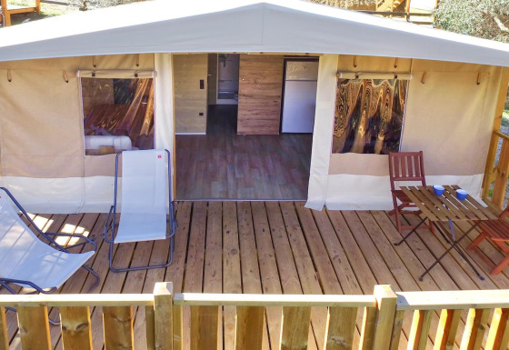 Safari Lodge Tent Deluxe avec terrasse en bois, chaises longues et coin repas, parfait pour le glamping.