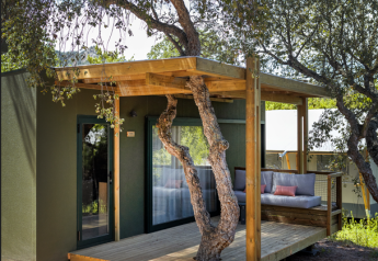 Photo au lodge Mobile Home Family avec terrasse en bois et un arbre traversant la toiture du porche.