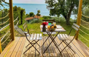 Wooden terrace of a safari tent with a breakfast table overlooking the lake at Vacanze Glamping Boutique, Italy.