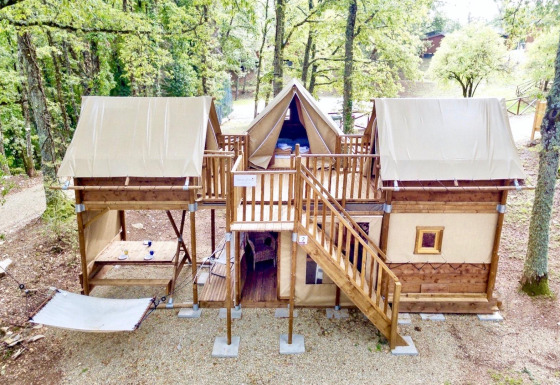 Safari-Zelt Air Dreamer 3 im Wald mit Holzstruktur, zwei Ebenen und einer Hängematte im Freien.