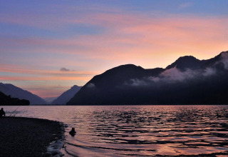 Solnedgang over søen ved Lago Idro Glamping Boutique, Lombardiet, Italien, med bjerge i baggrunden.