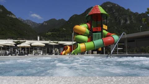 Vue sur une piscine avec des toboggans colorés et des montagnes en arrière-plan au Lago Idro Glamping Boutique.