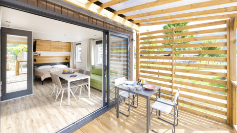 Lyst interiør og terrasse på Cube Suite XL i Lago Idro Glamping Boutique, Italien, med bord og stole.