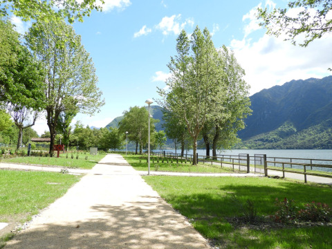 Park path overlooking the lake and mountains at Lago Idro Glamping Boutique, Lombardy, Italy, on a sunny day.